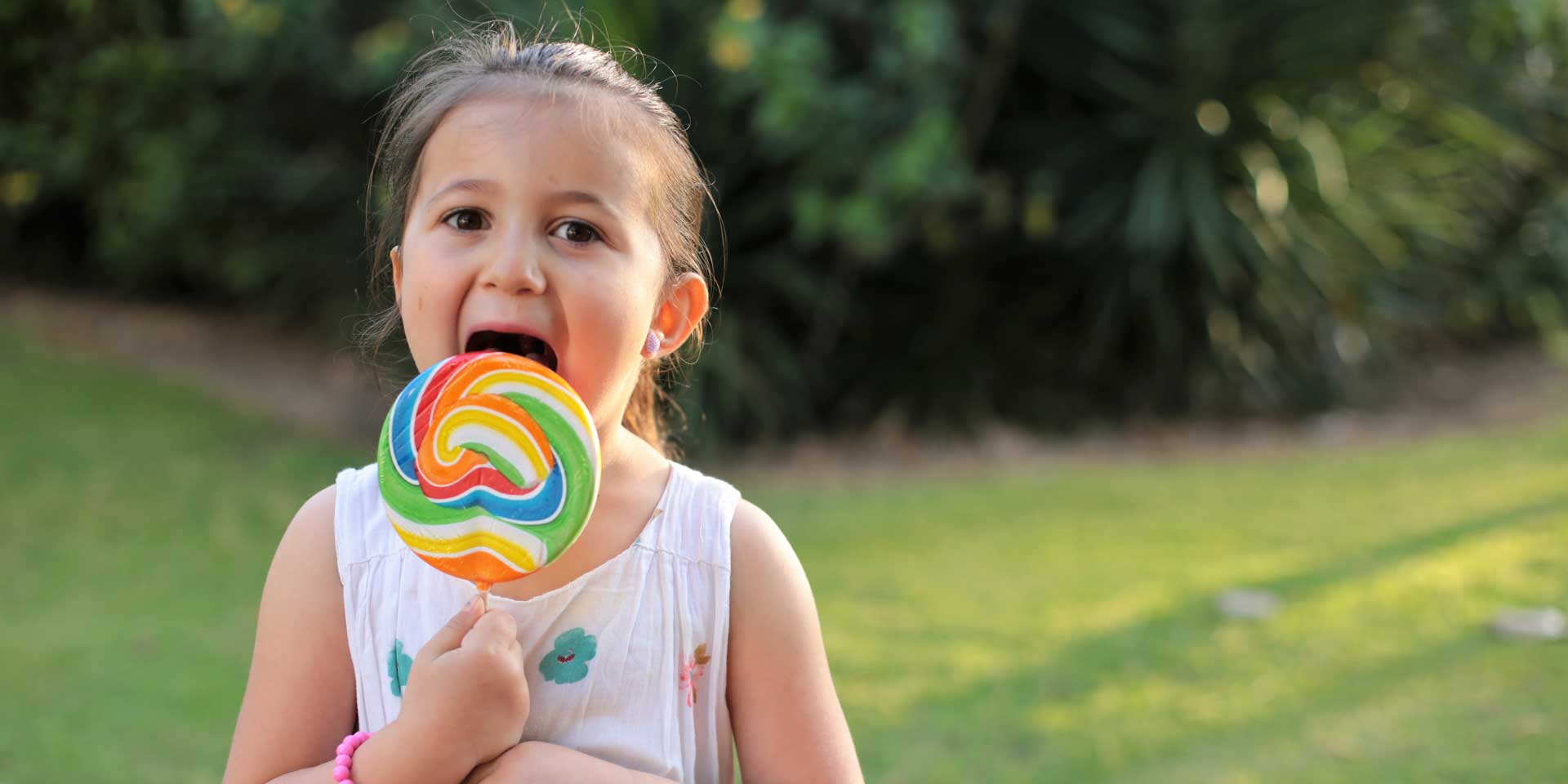 Girl licking a giant lollypop - all that sugar could lead to cavities.